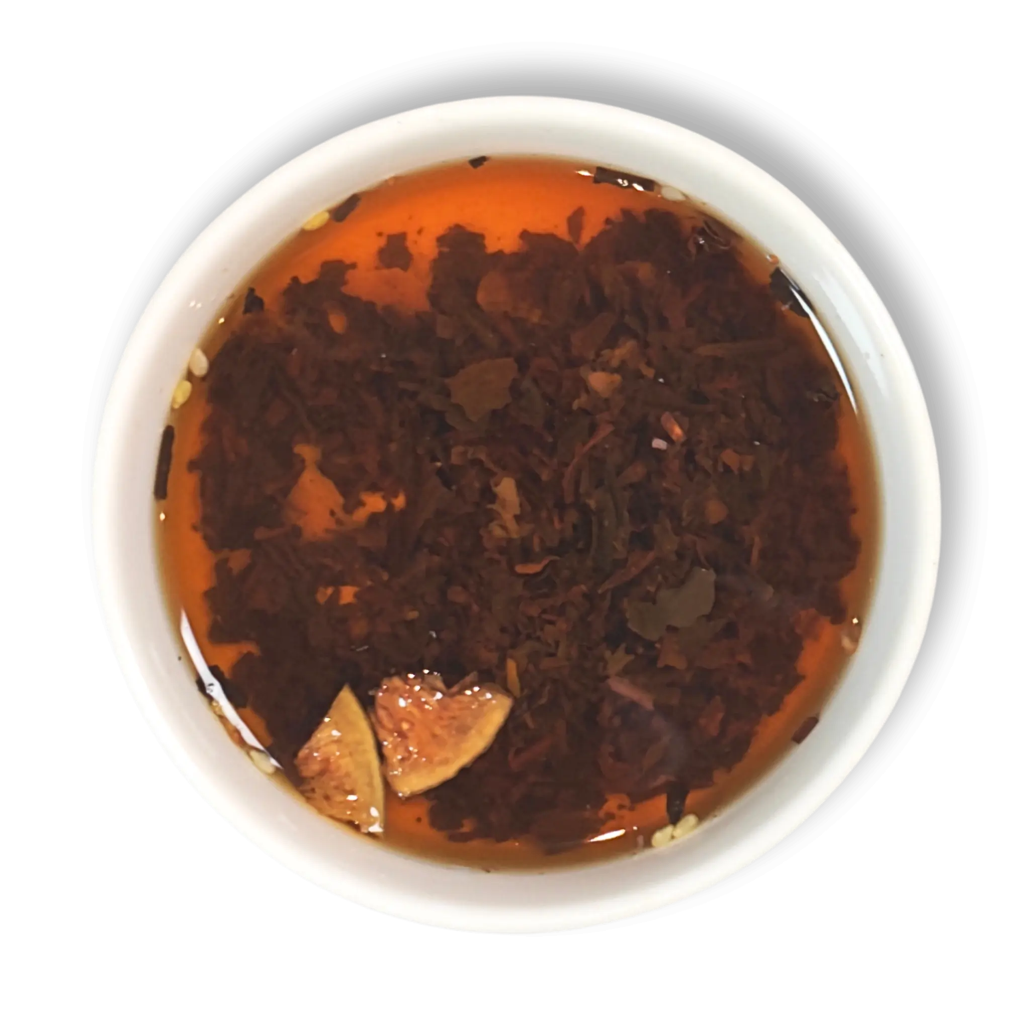 Top view of brewed Caravan of Palmyra loose leaf black tea in a white cup, showing amber liquor with floating fig and almond pieces.