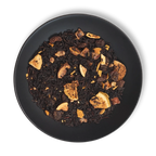 Caravan of Palmyra black tea blend close-up on black plate, featuring dried figs, dates, almond slices and loose leaf tea.