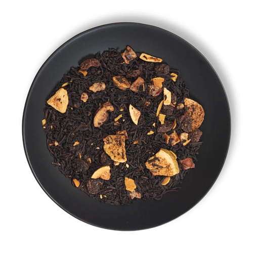 Caravan of Palmyra black tea blend close-up on black plate, featuring dried figs, dates, almond slices and loose leaf tea.