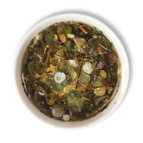 Top view of brewed Aether of Crete herbal tea showing whole Mediterranean herbs, citrus peel and dittany leaves in golden infusion.