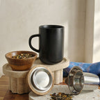 Juliet Black Stoneware Tea Mug 475ml with stainless steel infuser and acacia lid next to a loose-leaf tea bowl.