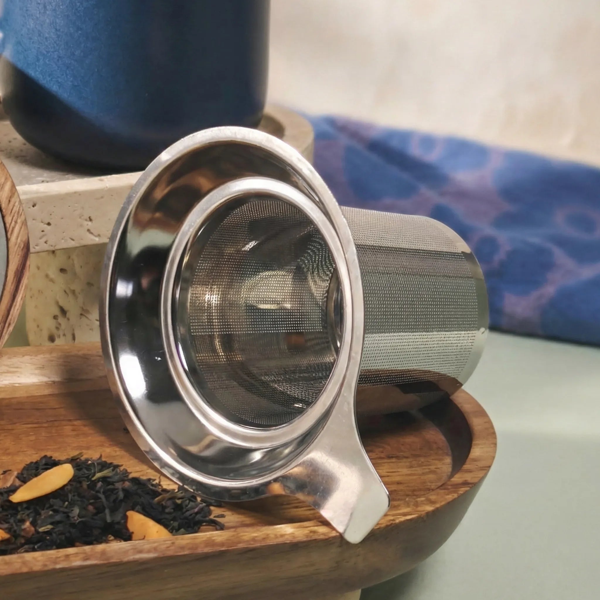 Detail of fine mesh stainless steel infuser for loose-leaf tea with Juliet Blue mug in background.