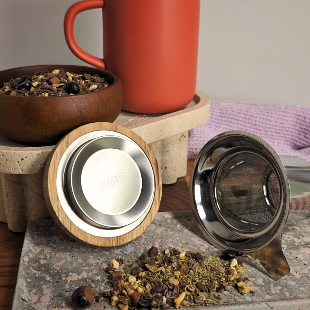 Underside of acacia lid showing OGO logo and stainless steel tea infuser displayed in front of Paprika red mug.