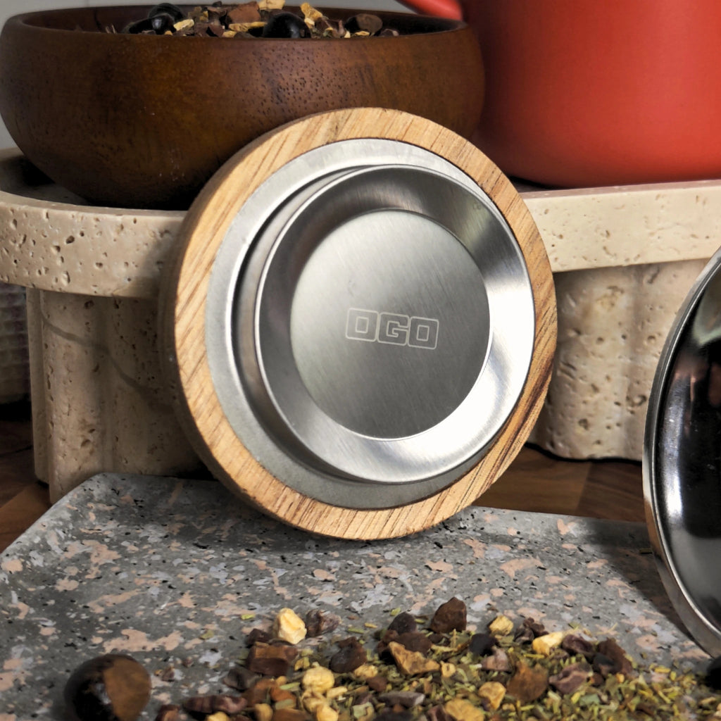 Close-up of natural acacia wood lid with stainless steel insert and loose tea blend.