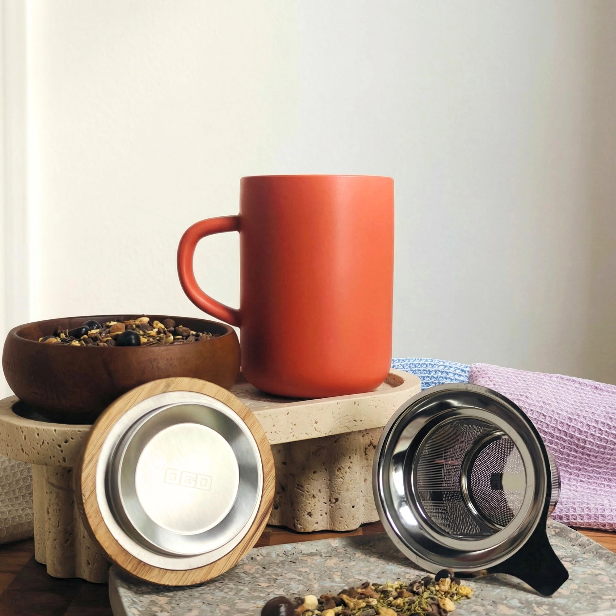 Juliet Paprika Stoneware Tea Mug 475ml with stainless steel infuser and acacia lid next to loose-leaf herbal tea.