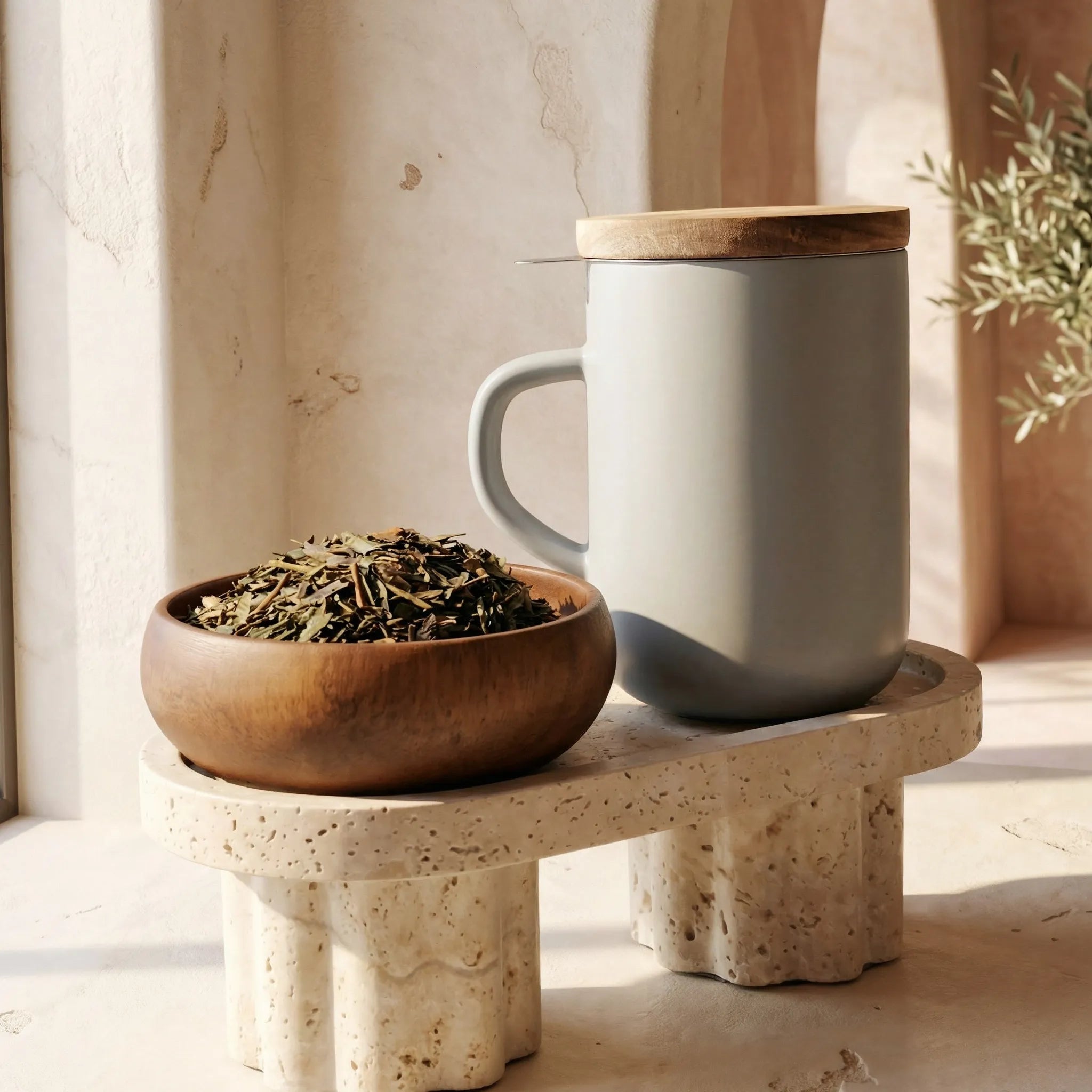 Minimal Perle grey stoneware Juliet mug with closed acacia wood lid for heat retention sitting on a terrazzo stand.