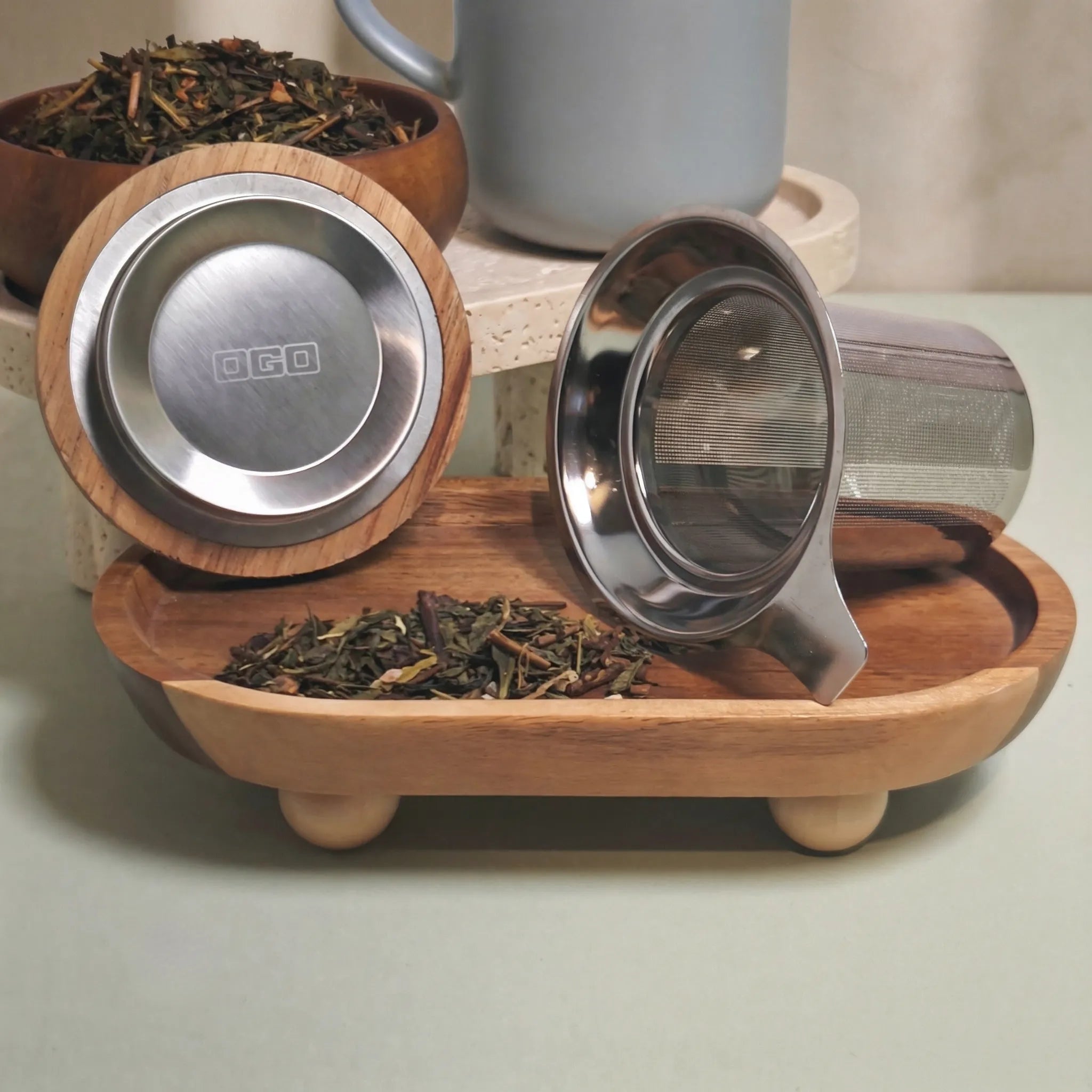 Juliet Perle tea mug set showing stainless steel infuser and acacia lid displayed on a wooden tray with loose tea.