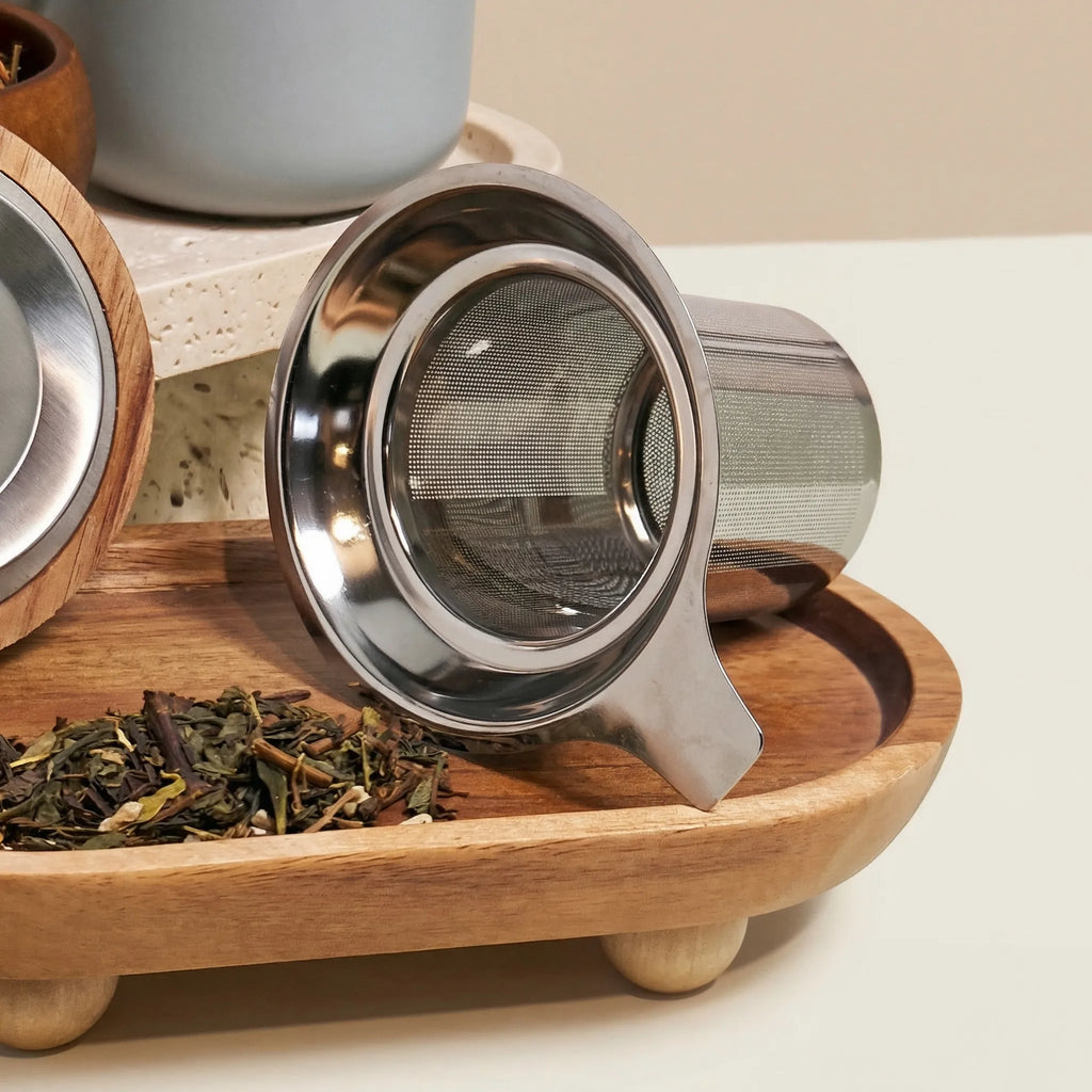 Detail of fine mesh stainless steel infuser for loose-leaf tea with Perle grey mug in background.
