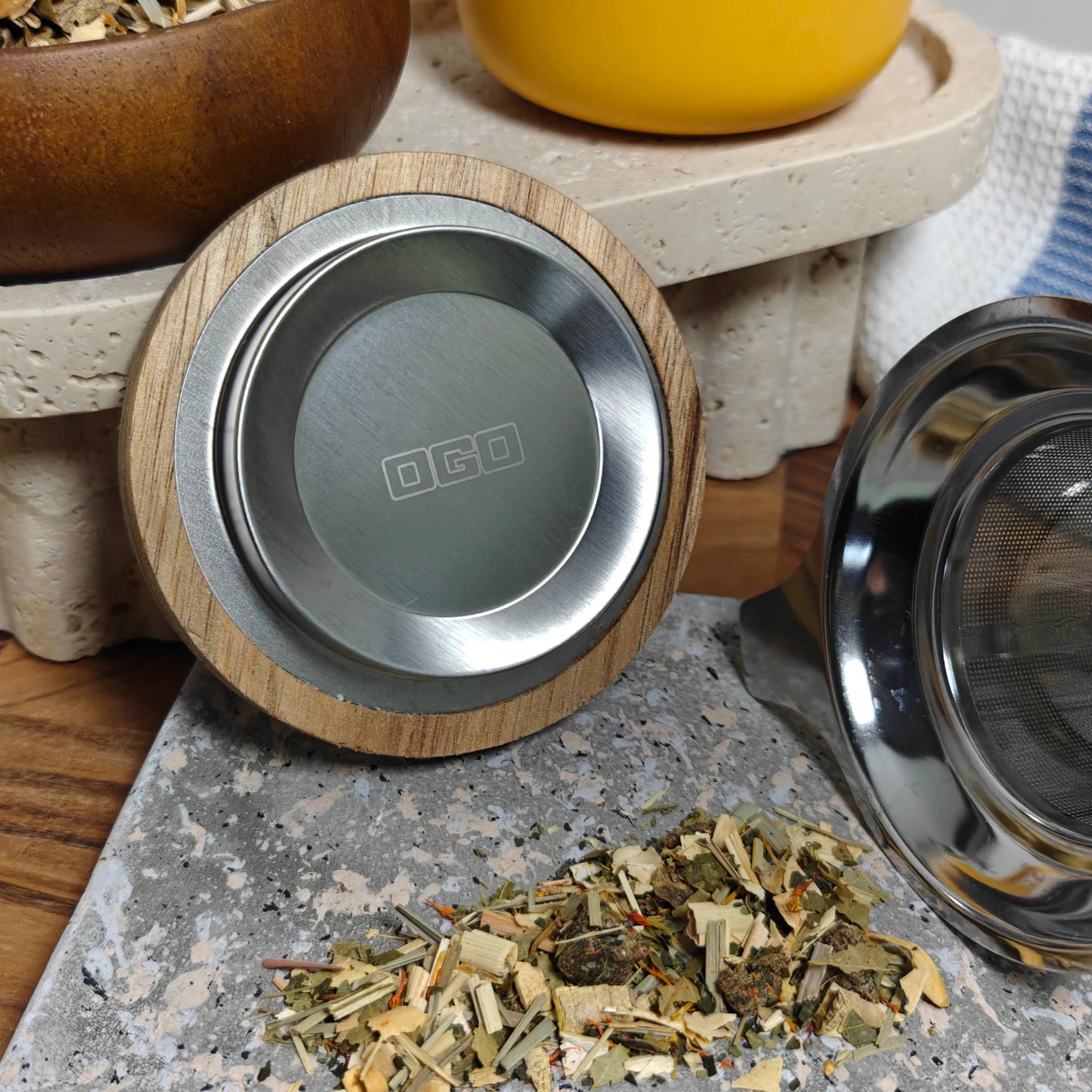Close-up of acacia wood lid with stainless steel insert and loose tea leaves.