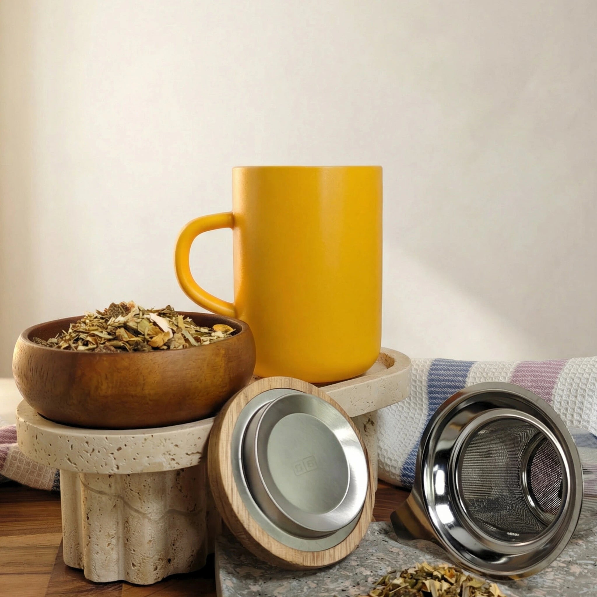 Juliet Yellow Stoneware Tea Mug 475ml with stainless steel infuser and acacia lid next to loose-leaf tea.