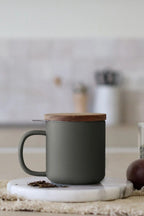 Juliet Khaki 300 ml tea mug with acacia lid on a table with loose-leaf tea
