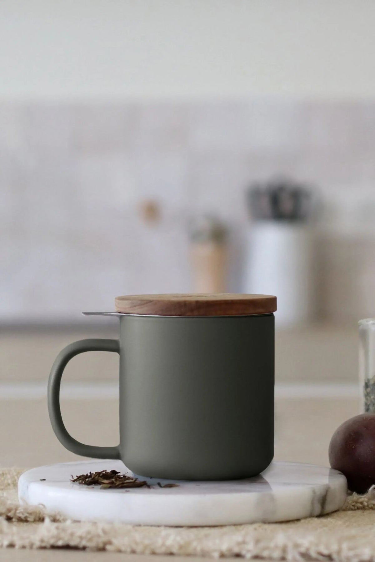 Juliet Khaki 300 ml tea mug with acacia lid on a table with loose-leaf tea