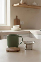 Juliet Khaki 300 ml tea mug with acacia lid on a table with loose-leaf tea