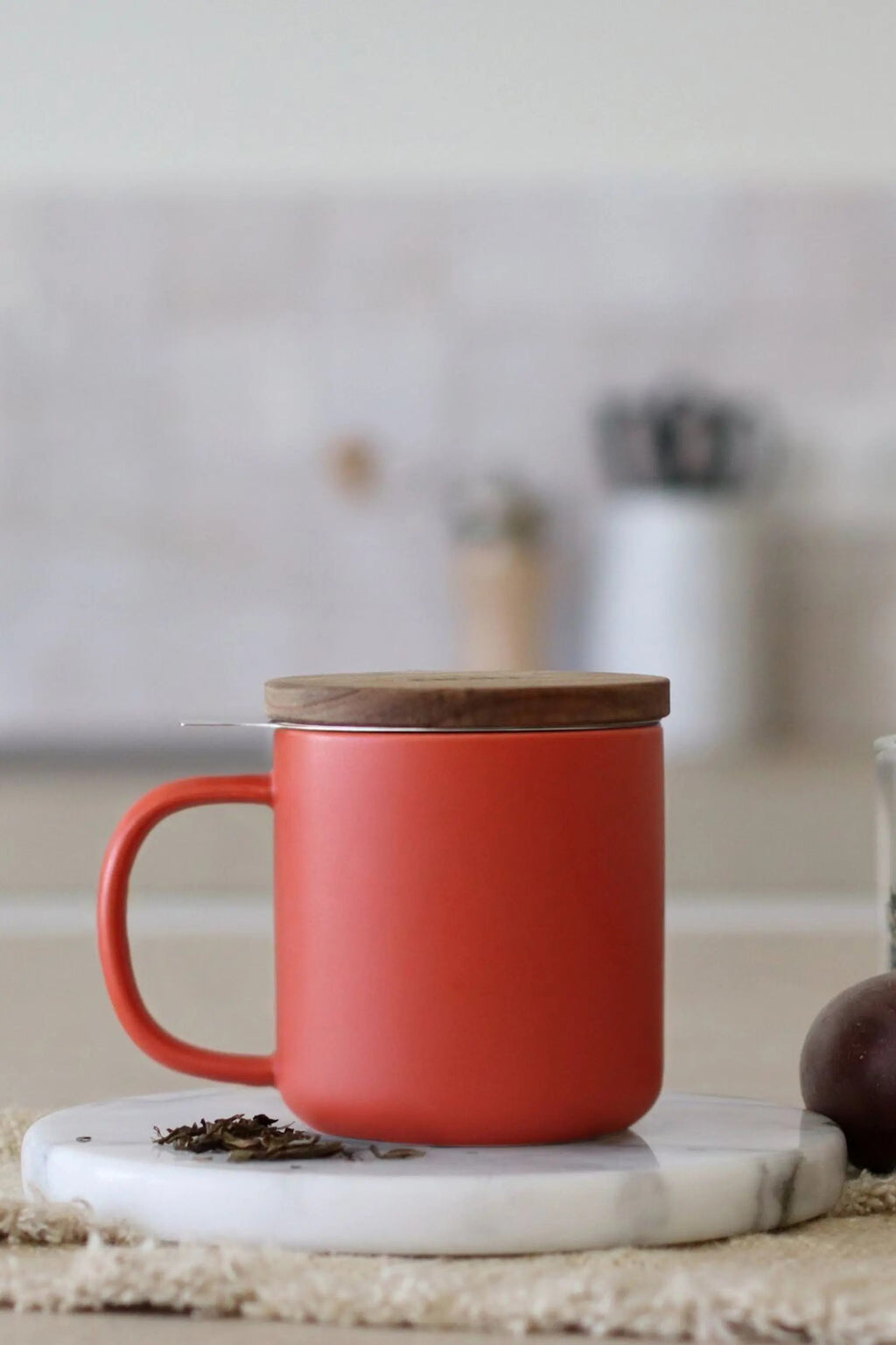 Juliet Paprika 300 ml tea mug with acacia lid on a table with loose-leaf tea