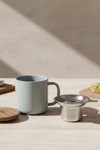 Juliet Perle 300 ml tea mug with acacia lid on a table with loose-leaf tea
