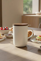 Juliet White 475 ml tea mug with acacia lid on a table with loose-leaf tea