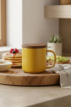 Juliet Yellow 300 ml tea mug with acacia lid on a table with loose-leaf tea